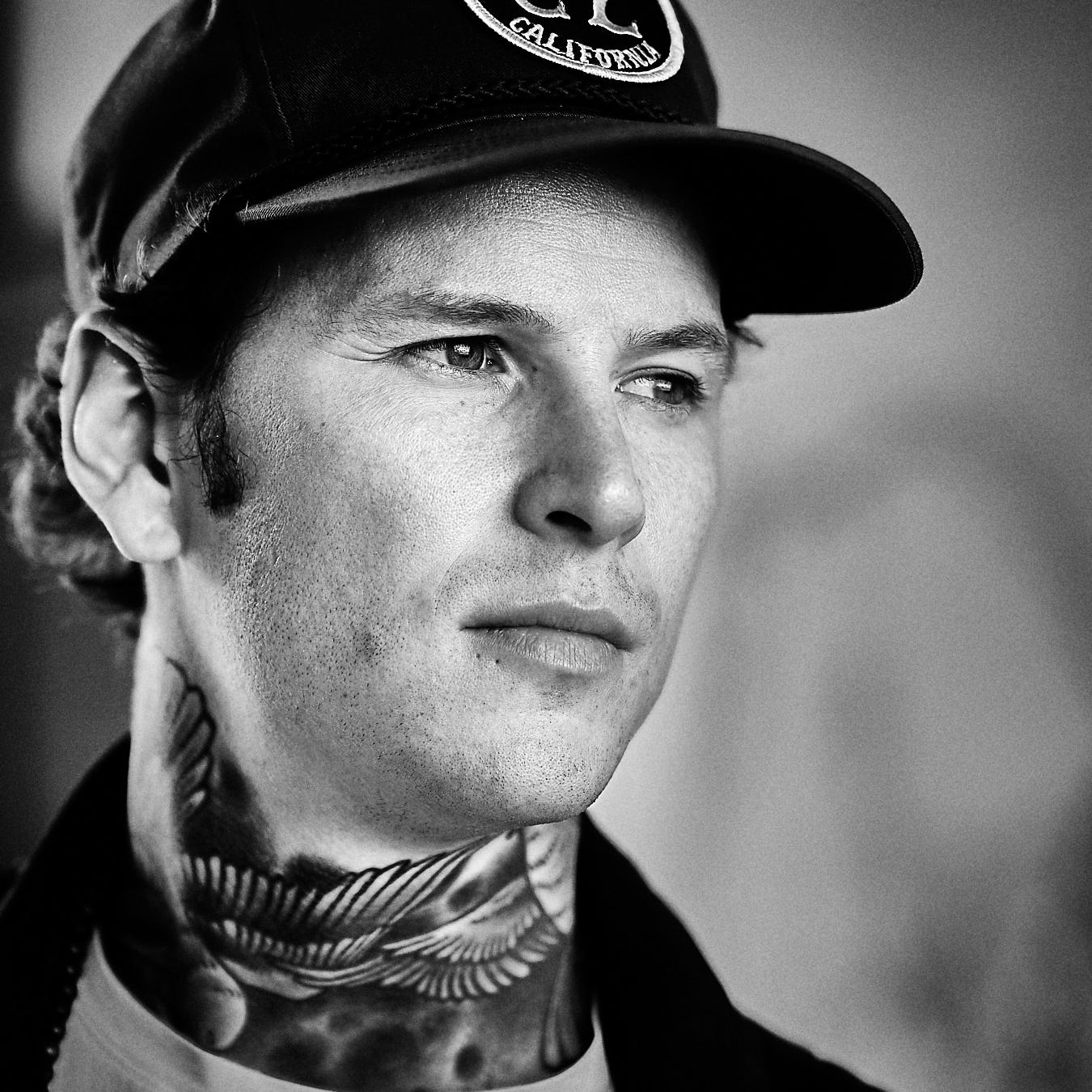 man with basball cap. he looks to the right into the far distance. he looks like he is lost in thoughts. picture is in black and white